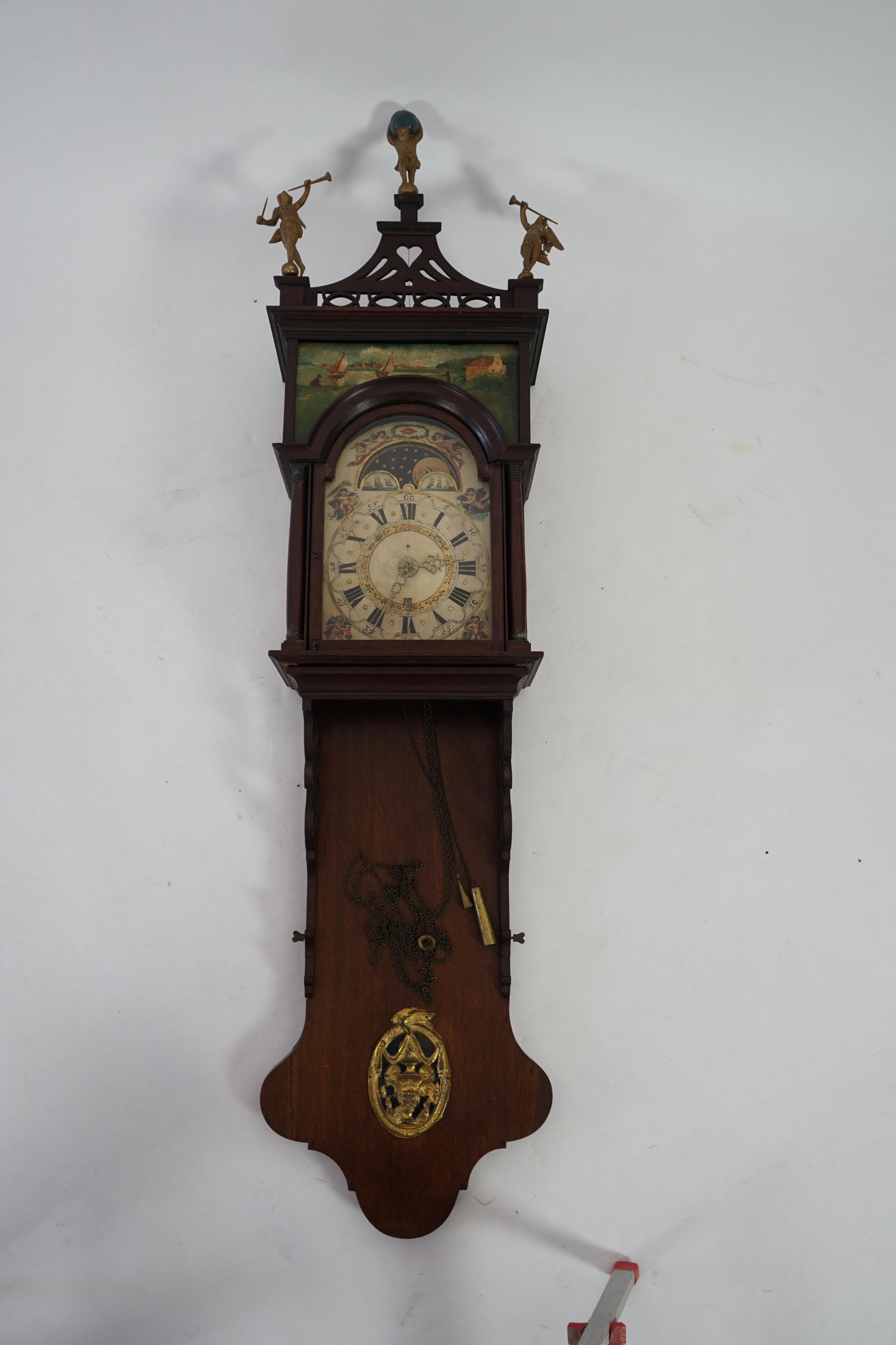 A late 18th century Dutch Frisian Staart oak eight day wall clock, with atlas and angel finials, hood painted with a Dutch riverscape and painted arched dial with moonphase, date aperture and alarm indicator, 47cm wide,